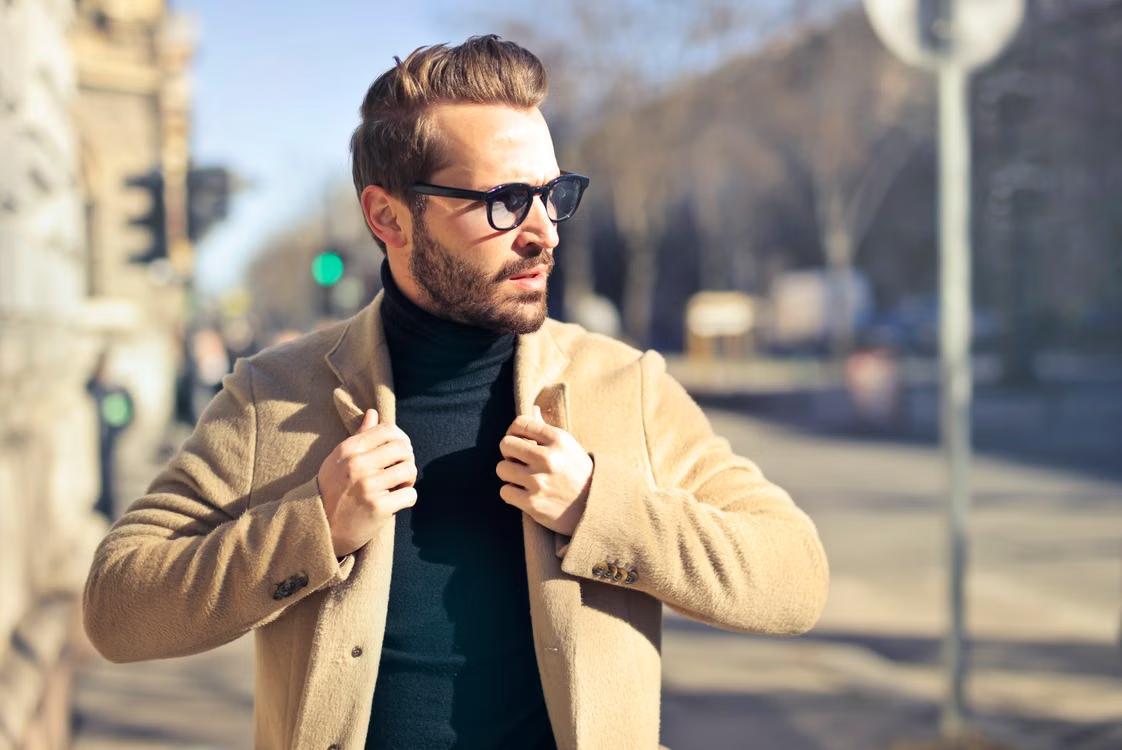 A man with a finely shaped beard and a brown coat. 