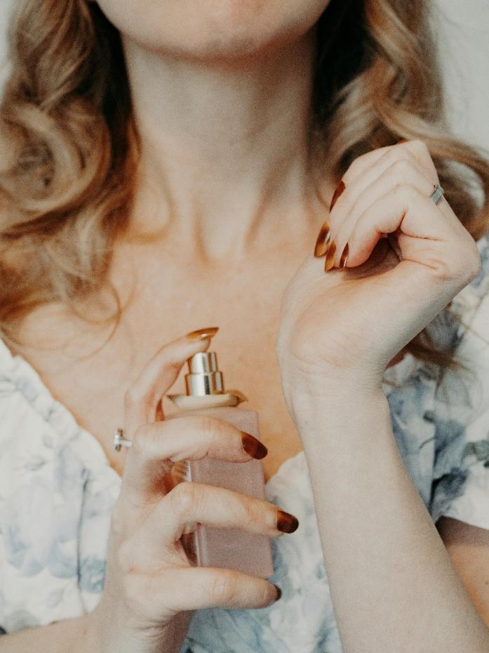 A person spraying perfume on neck A person spraying perfume on neck