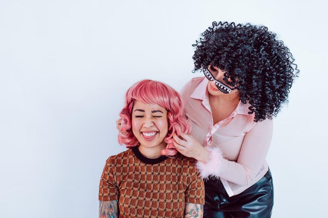 A person looks happy while getting a wig for their head. 