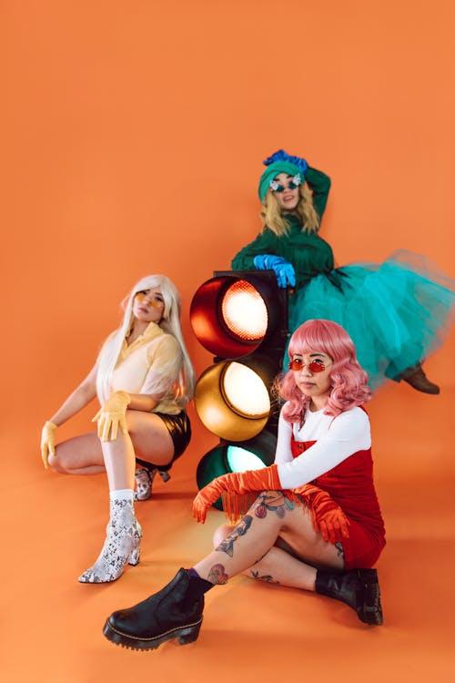 three models standing together wearing different colored wigs.